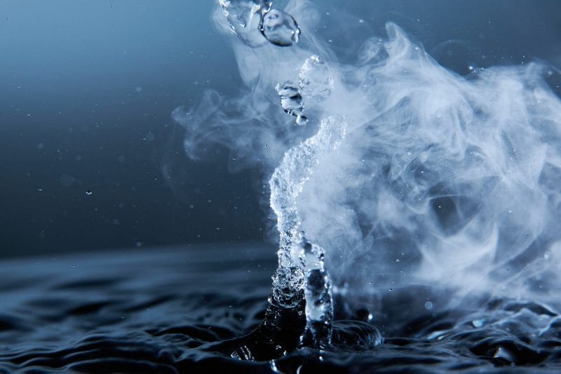 Steam rises from the dark blue surface of heated water.
