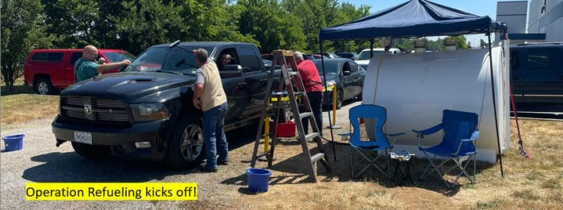 Jenfab team members fuel a black truck and wash its windshield during the refueling event. 
