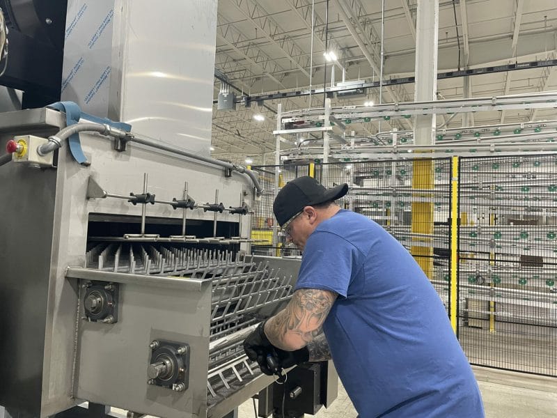 A maintenance technician inspects an aqueous parts washer.